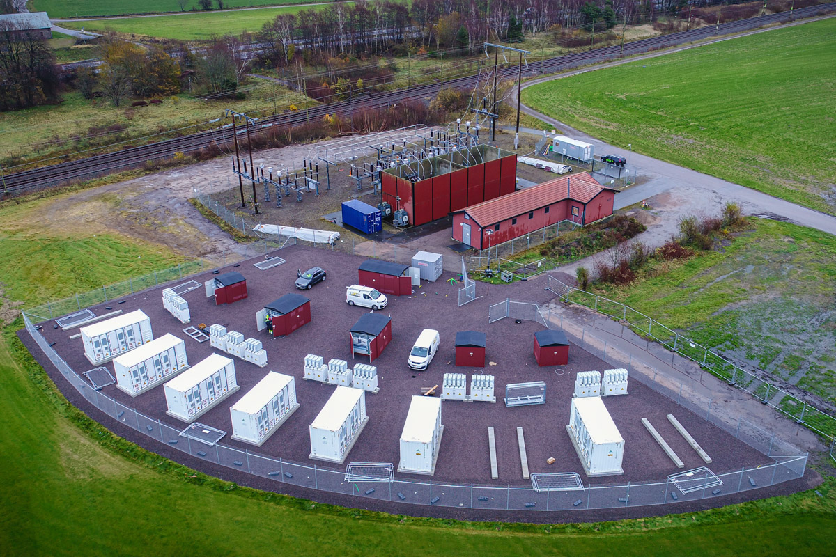 flygfoto över en batteripark intill en stor transformatorstation och järnvägsspår
