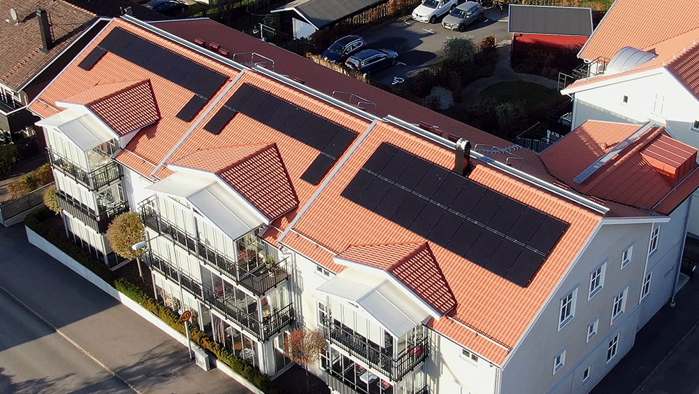 flygbild över flerfamiljshus med tre set solceller