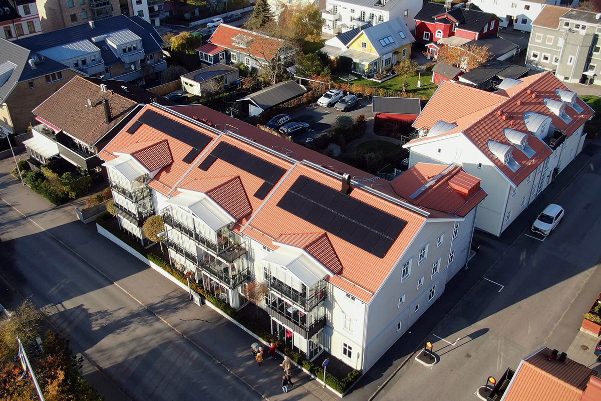 Flygbild över bostadsområde med solcellsanläggning på taken.