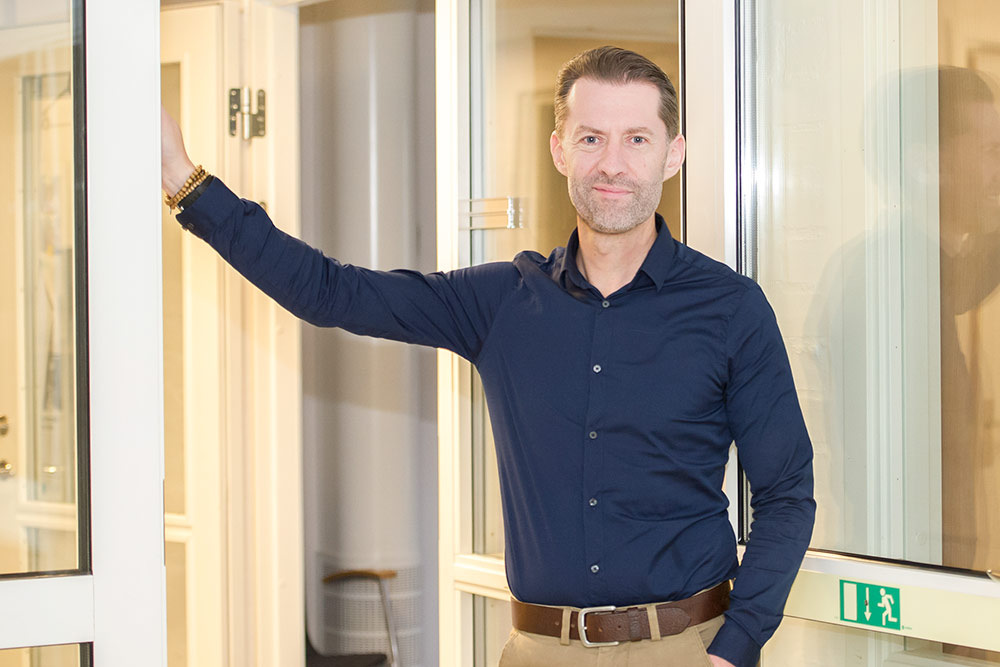 Mattias Svahn står i en dörröppning och lutar ena handen mot dörrkarmen, tittar i kameran