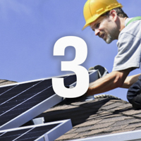 Montör sitter på ett tak och placerar ut solceller och siffran 3 framför