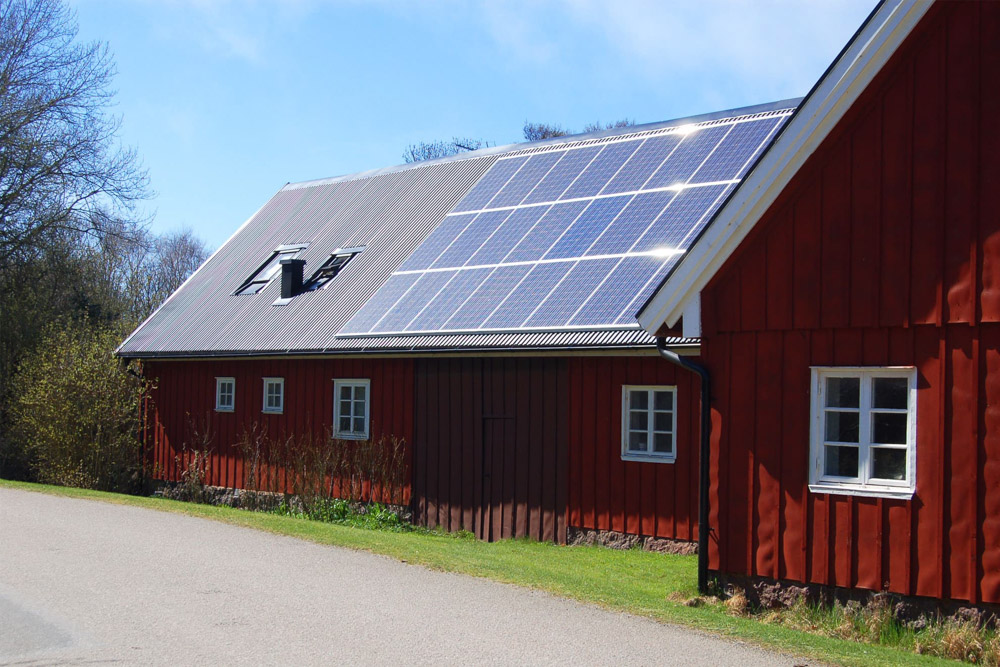 Gammal ladugård i solsken med solceller på taket