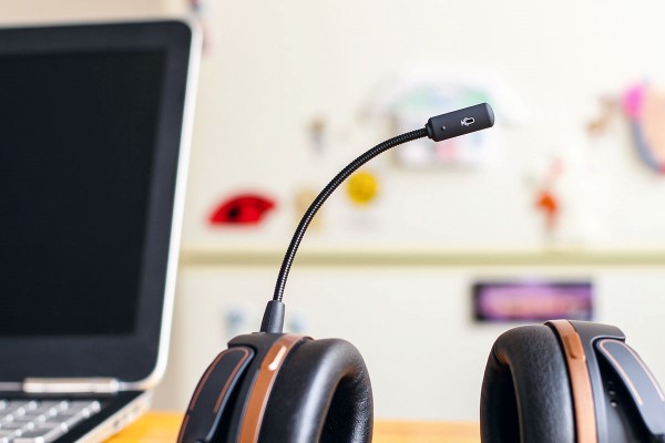 hörlurar med mikrofon ligger på ett kontorsbord bredvid en datorskärma