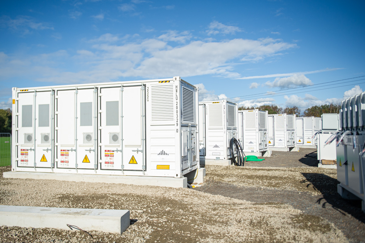 Batteripark med ett antal stora vita containrar innehållande batterier ståendes på rad.